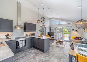 A modern kitchen with a central island, built-in appliances, and a dining area with a view.