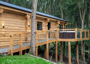 A wooden cabin with a deck and a hot tub.