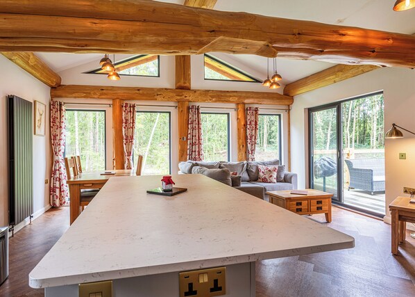 A spacious kitchen with a large island, wooden beams, and large windows offering views of the outdoors. - 2 bedroom accommodation in Ellesmere (Ellesmere)