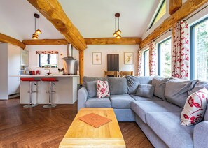Uma cozinha moderna com ilha central, um sofá modular cinza e piso de madeira.
