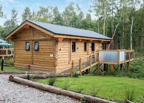 A wooden cabin with a deck, surrounded by a forest. - 2 bedroom accommodation in Ellesmere (Ellesmere)