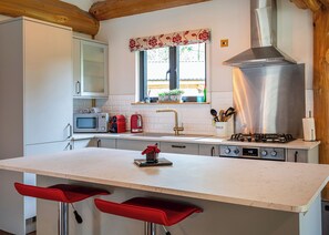 A kitchen with a central island, a microwave, a toaster, a gas stove, and a window with a view of greenery outside. - 2 bedroom accommodation in Ellesmere (Ellesmere)