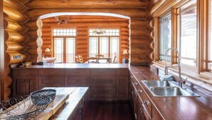 A log cabin interior with a central island kitchen, wooden cabinets, and large windows. - EXCLUSIVE very private cabin on the golf course! (Panorama)