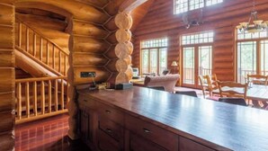 A log cabin interior with a wooden staircase, a large kitchen island, and a dining area with wooden furniture. - EXCLUSIVE very private cabin on the golf course! (Panorama)
