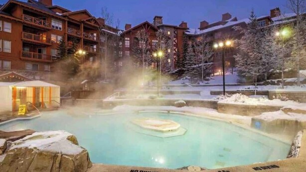 A heated outdoor pool surrounded by wooden buildings with balconies, a sauna area, and a sign indicating no diving. - EXCLUSIVE very private cabin on the golf course! (Panorama)