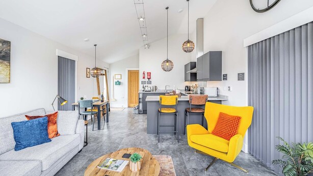 Una sala de estar moderna con un sofá, una mesa de centro y una silla de color amarillo brillante.