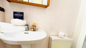 Ett badrum med ett vitt handfat, en toalett och en gul badrumsmatta.