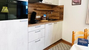 Une cuisine compacte avec des meubles blancs, un plan de travail en bois et un four encastré.
