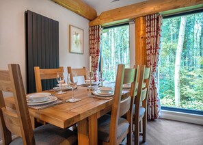 A dining table set with chairs, a framed picture on the wall, and a window with curtains.