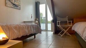 A bedroom with two beds, a chair, a table, and a painting on the wall. - Charming 2-Bedroom Cottage Near Guérande and La Baule Beaches, with Terrace and WiFi (Guérande)