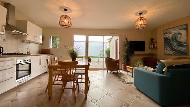A modern kitchen with a dining area, a living room with a sofa, and a large window with a view of the outdoors. - Charming 2-Bedroom Cottage Near Guérande and La Baule Beaches, with Terrace and WiFi (Guérande)