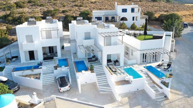A modern white building with multiple balconies and a swimming pool area.
