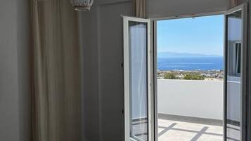Ein Schlafzimmer mit einem großen Bett, Blick durch eine Schiebetür auf einen Balkon und zwei Pendelleuchten.