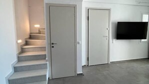 A modern interior with a staircase, two white doors, and a flat-screen TV mounted on the wall.
