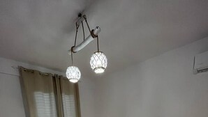 A bedroom with a bed, curtains, and a ceiling light fixture.