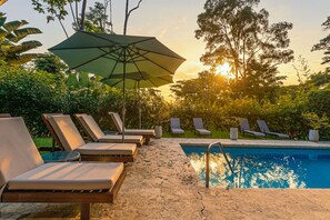 A poolside area with lounge chairs and an umbrella.