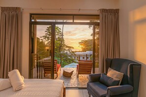 A bedroom with a bed, a chair, and a view of the outside.