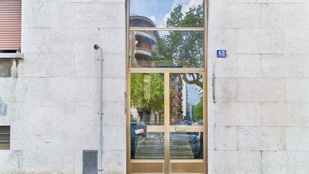 A building entrance with a glass door, a visible number '63' sign, and a metal utility box. - GuestHost - JJ'S Place Trieste Apartment (Trieste)