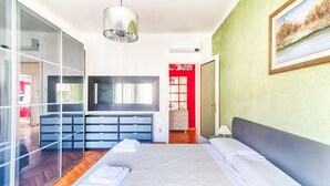 A bedroom with a bed, a dresser, a mirror, and a painting on the wall. - GuestHost - JJ'S Place Trieste Apartment (Trieste)