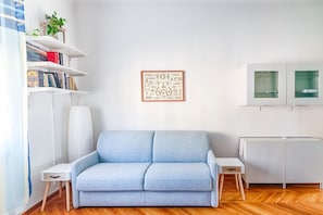 A living room with a sofa, a small table, a cabinet, and a bookshelf.