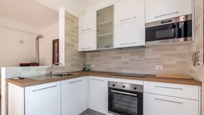 Eine moderne Küche mit weißen Schränken, einem Edelstahlbackofen und einer Holzausziehtafel.