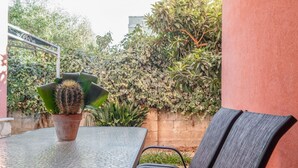 Eine Terrasse mit einem Glastisch, einem Metallstuhl und einem Topf mit einem Kaktus.