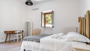 Ein Schlafzimmer mit Bett, Schreibtisch, Stuhl, Fenster und Heizkörper.