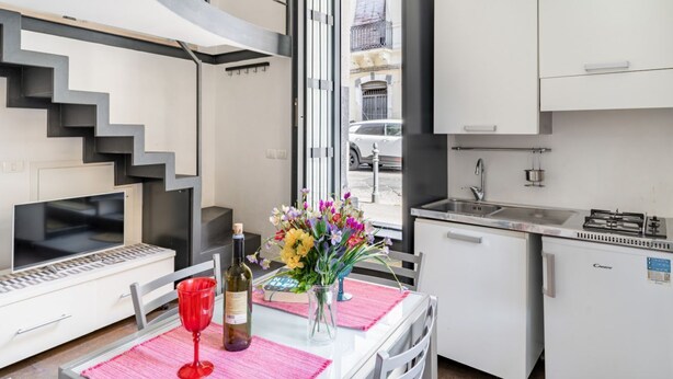 A compact kitchen with a dining area, a built-in stove, and a view through an open door. - GuestHost - Catania Central Design Studio near the Station (Catania)