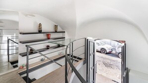 A modern interior with a staircase, glass railings, and a view of a parked car outside. - GuestHost - Catania Central Design Studio near the Station (Catania)
