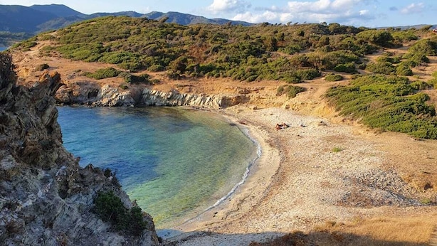 A coastal landscape with a clear beach, rocky outcrops, and distant hills. - Modern villa with garden in charming South Sardinia (Teulada)