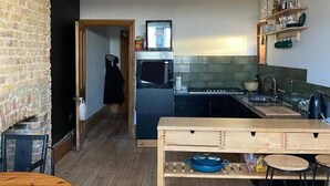 A modern kitchen with a wooden table, a built-in oven, and a hanging light fixture. - Edwardian Villa by the Sea,coastal Walks,king Beds (Walton on the Naze)