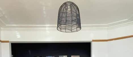 Un salón con pared azul oscuro, una lámpara colgante de metal negro, dos sofás negros, una mesa de centro de madera y una lámpara de pie negra.