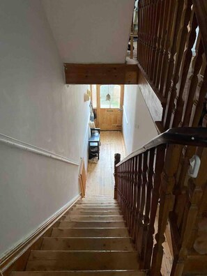 A wooden staircase with a handrail leading to a door with a window.