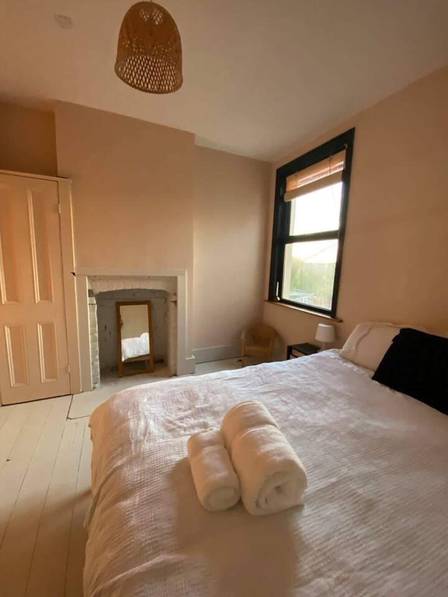 A bedroom with a bed, a window, a fireplace, and a door.