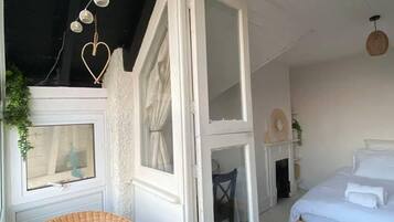 A bedroom with a bed, a wicker chair, and a window with curtains.