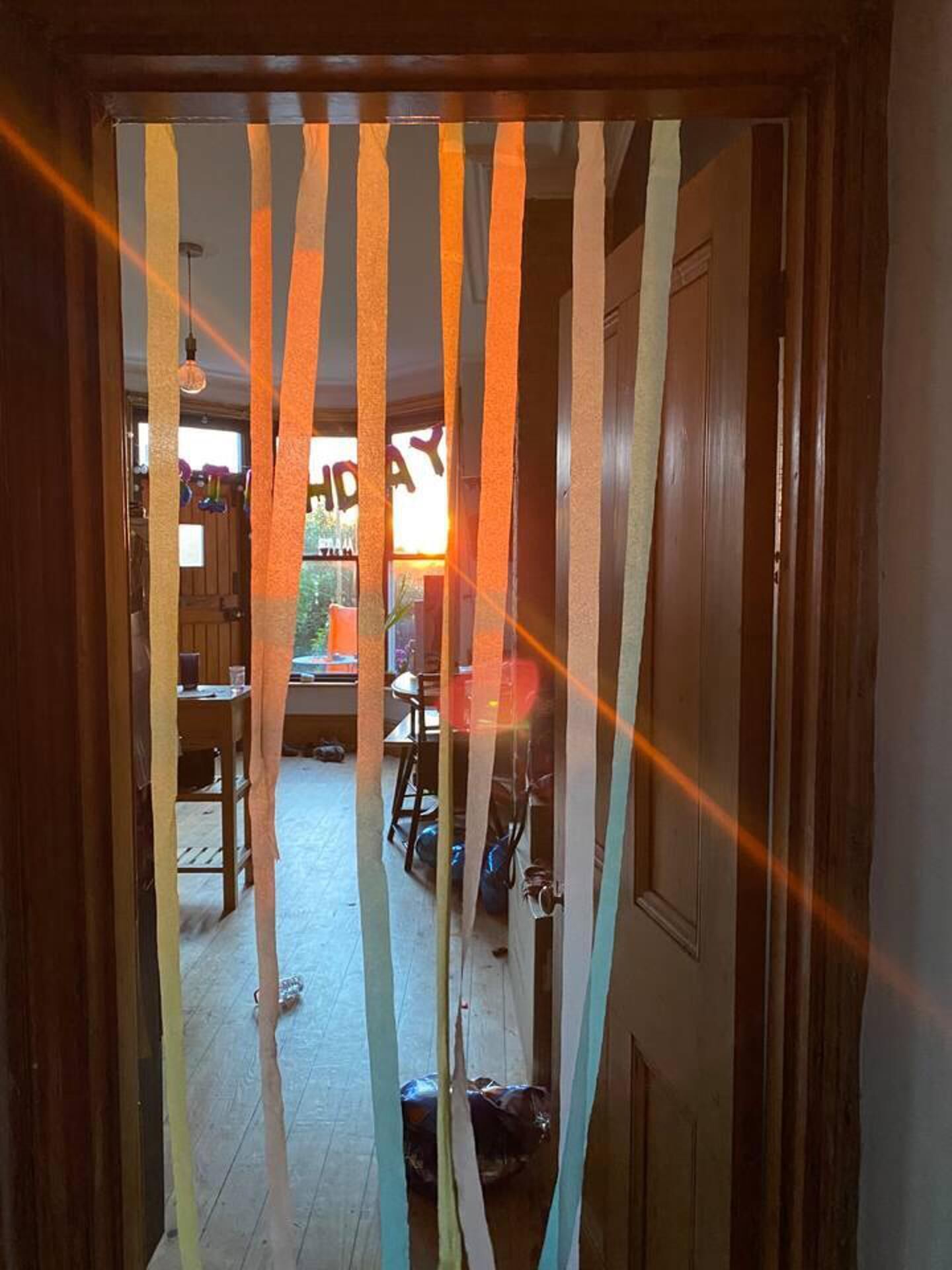 A hallway with wooden doors and a view into a room with a table and chairs.
