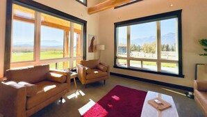 A spacious living room with large windows, a red rug, and leather sofas. - Eagle Cap Farms hosted owned and operated by Eagle Cap Vacation Rentals (Joseph)