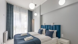 Ett modernt hotellrum med en stor säng, två sängbord och ett litet bord.