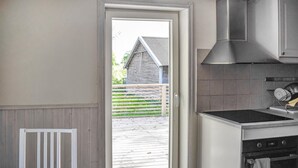 A kitchen with a stove, oven, and a door leading to an outdoor wooden deck.