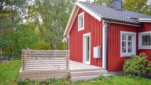 A red wooden house with a wooden deck and a white door.