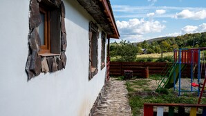 A rustic building with stone steps leading to a wooden door, a playground with colorful equipment, and a clear sky.