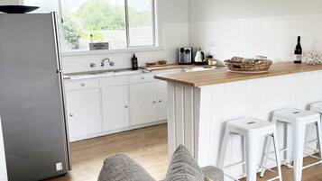 Une cuisine moderne avec des meubles blancs, un réfrigérateur en acier inoxydable et un plan de travail en bois.