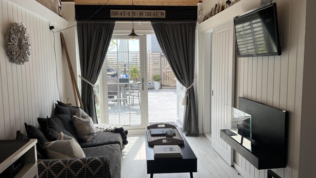 A modern living room with a sofa, coffee table, and TV. A sliding glass door leads to an outdoor area. - Seaside Cabin Retreat in Hayling Island (Hayling Island)