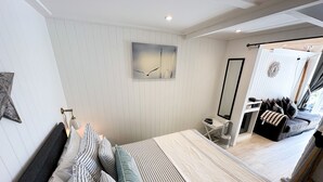 A modern bedroom with a large bed, a bedside table, a mirror, and a view of a balcony. - Seaside Cabin Retreat in Hayling Island (Hayling Island)