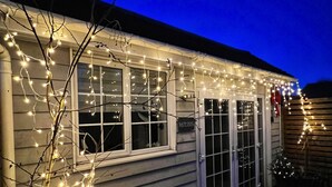 A house with a porch, decorated with string lights. - Seaside Cabin Retreat in Hayling Island (Hayling Island)
