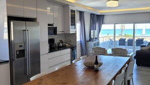 Una cocina moderna con electrodomésticos de acero inoxidable, una mesa de comedor de madera y sillas blancas.