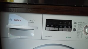 Een Bosch wasmachine met een bedieningspaneel waarop temperatuur, snelheid en instellingen worden weergegeven.