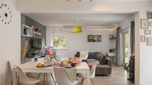 Een moderne woonkamer met een eethoek, met een bank, salontafel en een boekenkast.