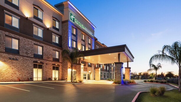 Un hotel Holiday Inn Express con fachada de ladrillo, amplias ventanas y una zona de entrada cubierta.
