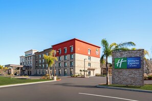 Edifício do Holiday Inn Express & Suites com telhado vermelho e fachada de pedra bege.